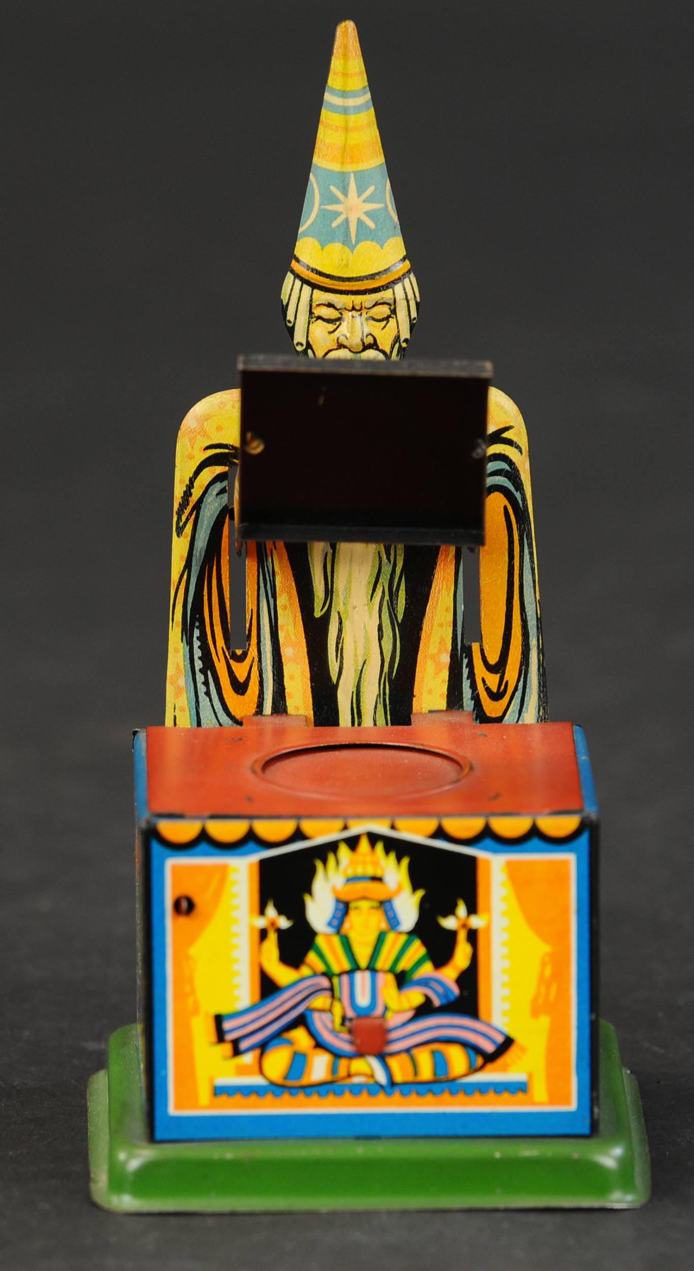 MAGIE TIN MECHANICAL BANK: 243. MAGIE TIN MECHANICAL BANK | Germany, desirable tin bank, pressing lever causes magician to lower tray over coin then raise it as coin disappears into money box. Provenance: Griffith to Bob Weiss 