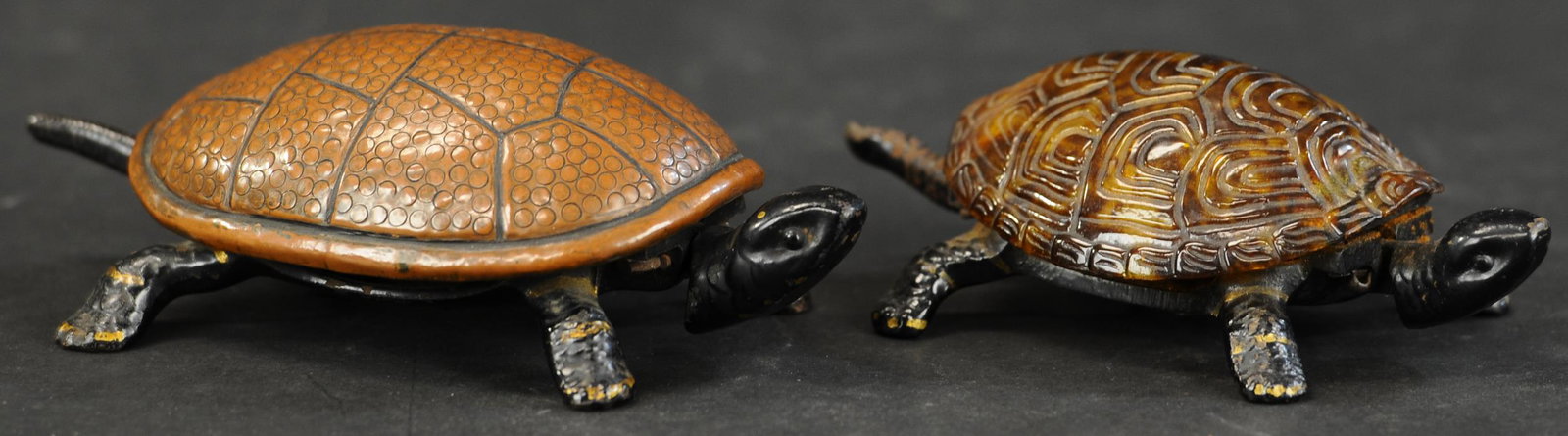 TWO TURTLE DESK BELLS: 324. TWO TURTLE DESK BELLS | A Gong Bell turtle and a celluloid shell turtle, wind up and tap the tails to ring bell, detailed castings. 6" - 7" l. | (Excellent Condition) | $400 - $600