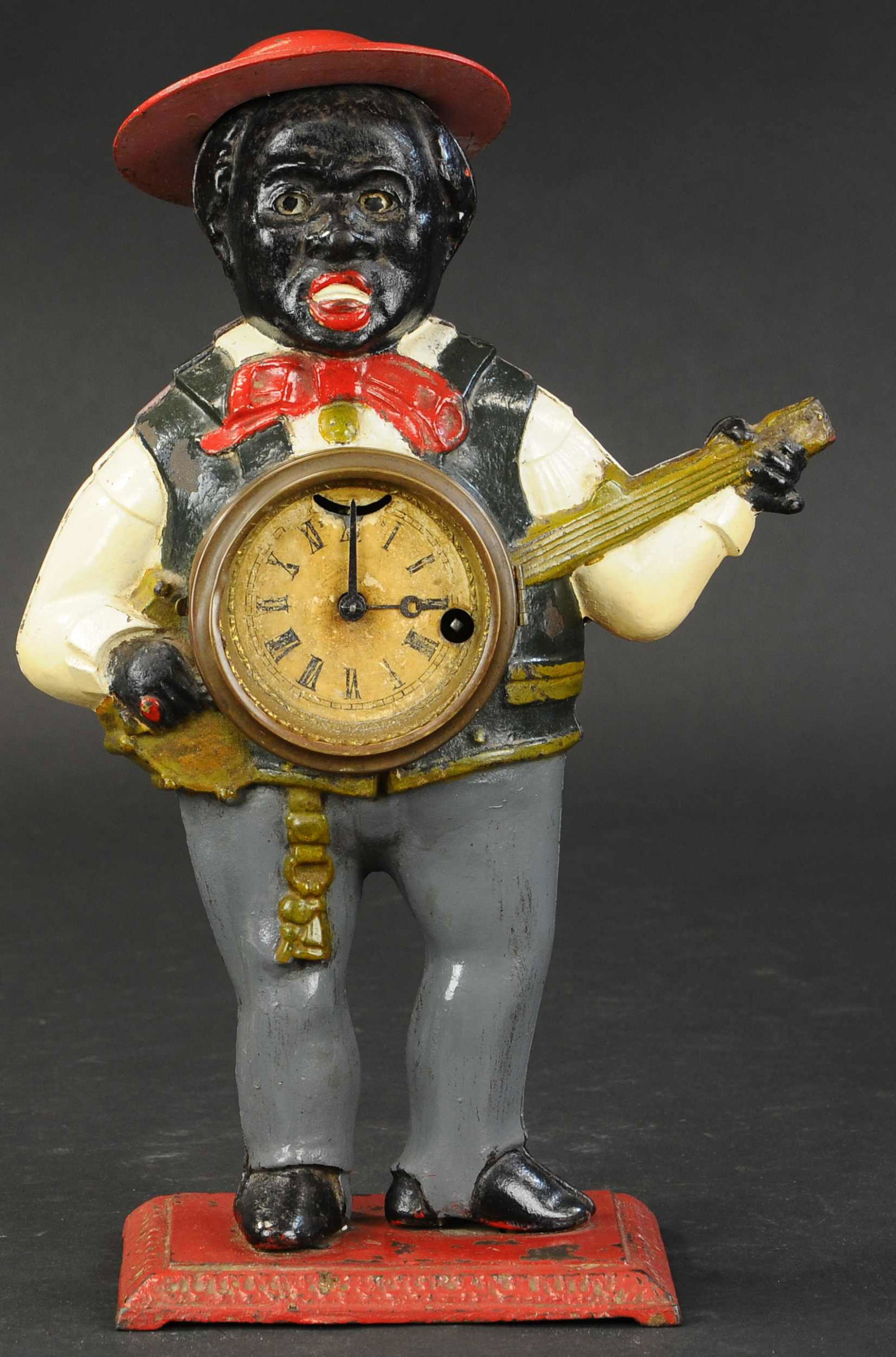 SAMBO CLOCK WITH BLINKING EYES: 328. SAMBO CLOCK WITH BLINKING EYES | Bradley & Hubbard, cast iron full figure of man playing banjo with clock face, a classic American design with extensive casting effects, two part molded body. 16"