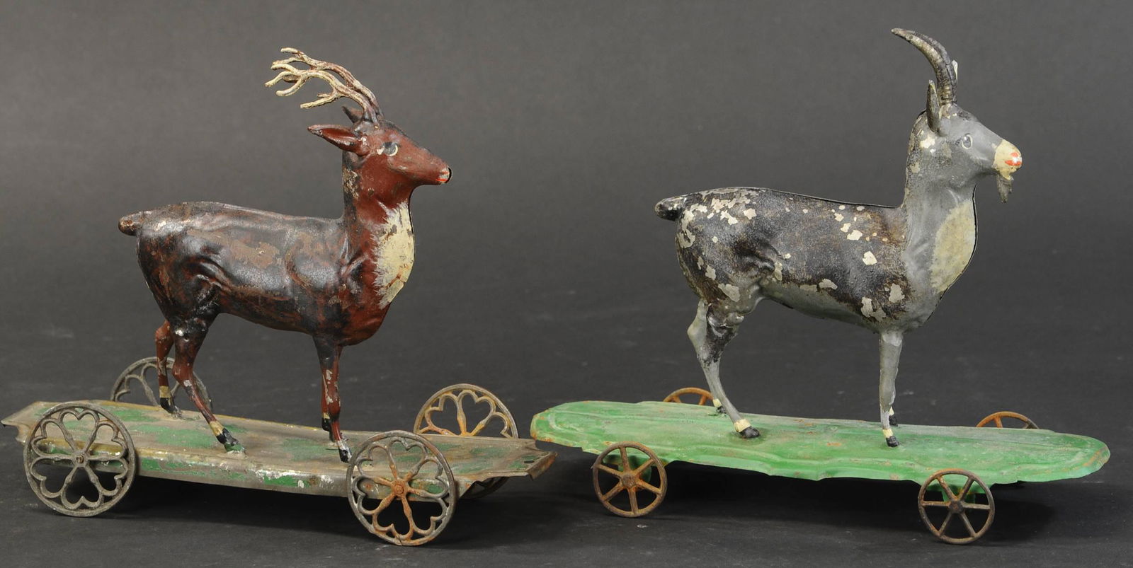 DEER & GOAT PLATFORM TOYS: 419. DEER & GOAT PLATFORM TOYS | Two early American painted tin pull toys of stately and familiar animals standing atop wheeled platforms. 10" l. | Overall in (Very Good Condition) | $600 - $900