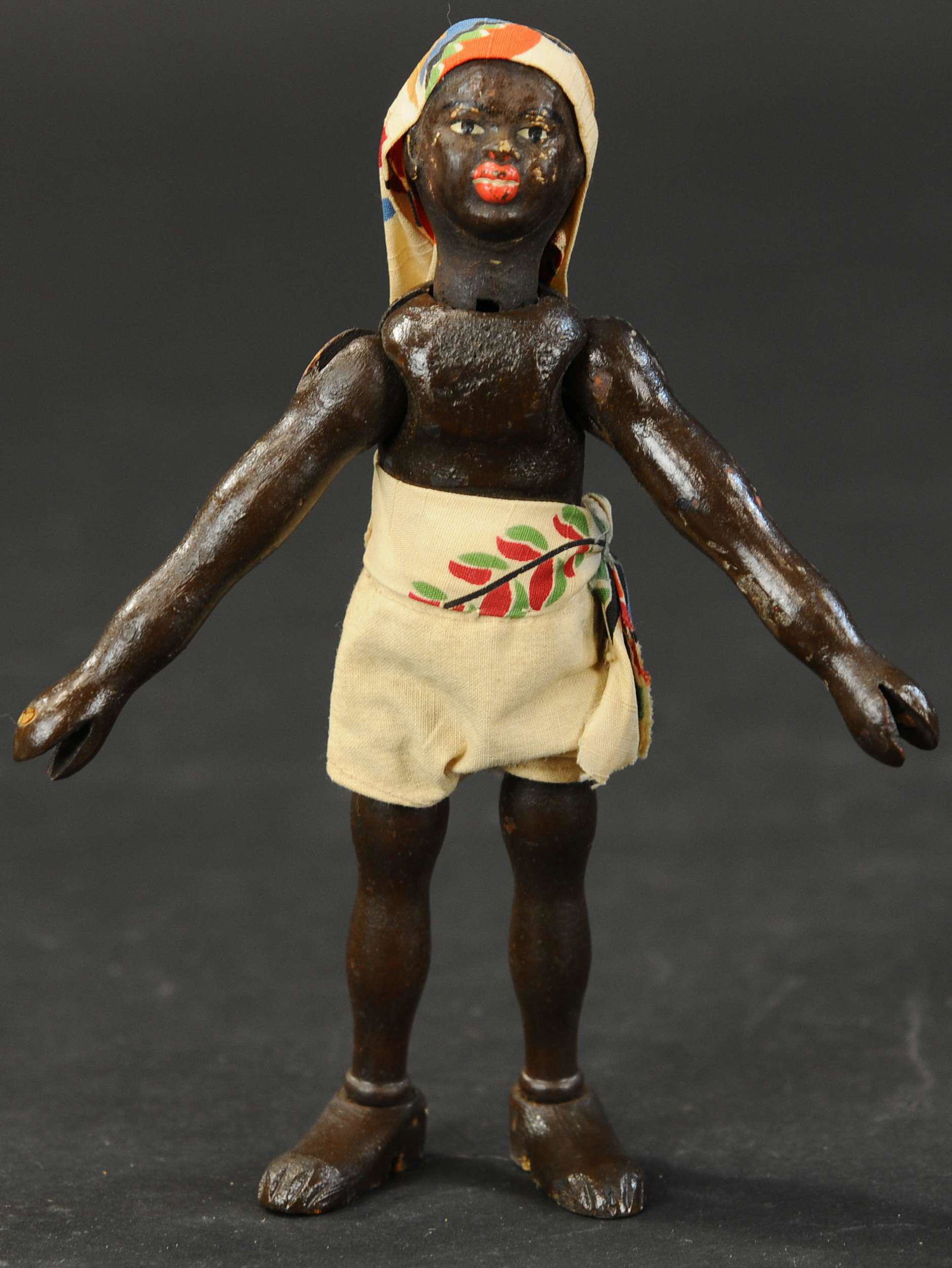 SCHOENHUT AFRICAN NATIVE SAFARI FIGURE: 490. SCHOENHUT AFRICAN NATIVE SAFARI FIGURE | Wood jointed, two part head, closed mouth, hand painted, wearing khaki shorts, colorful sash and headdress, rare figure. 8"h. | (Excellent Condition) | $1