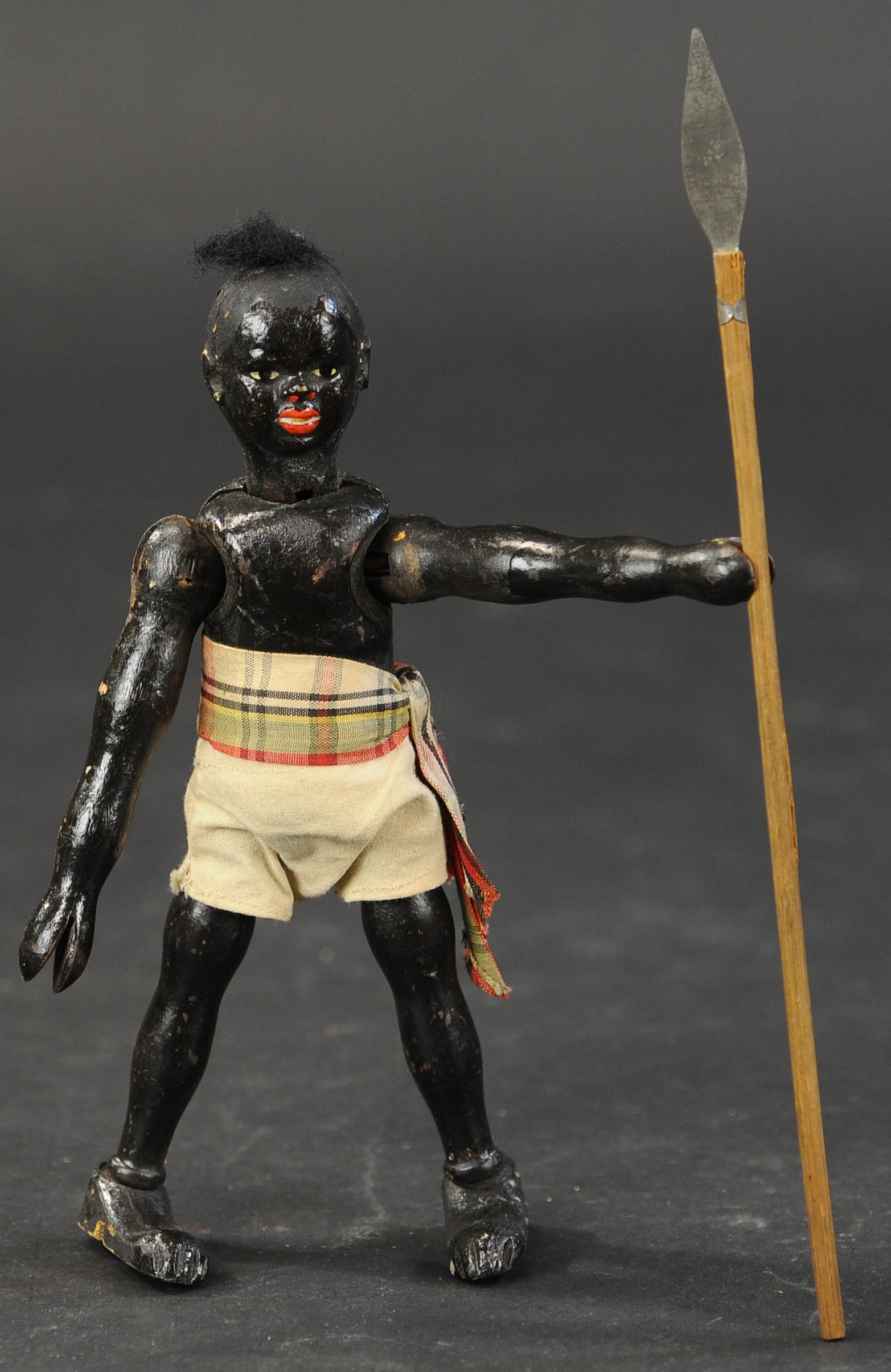 SCHOENHUT AFRICAN NATIVE W/SPEAR: 514. SCHOENHUT AFRICAN NATIVE W/SPEAR | Wood jointed, two part head, closed mouth, hand painted, wearing khaki shorts and sash, carrying a spear, rare. 8"h. | (Excellent to Pristine Condition) | $1,00