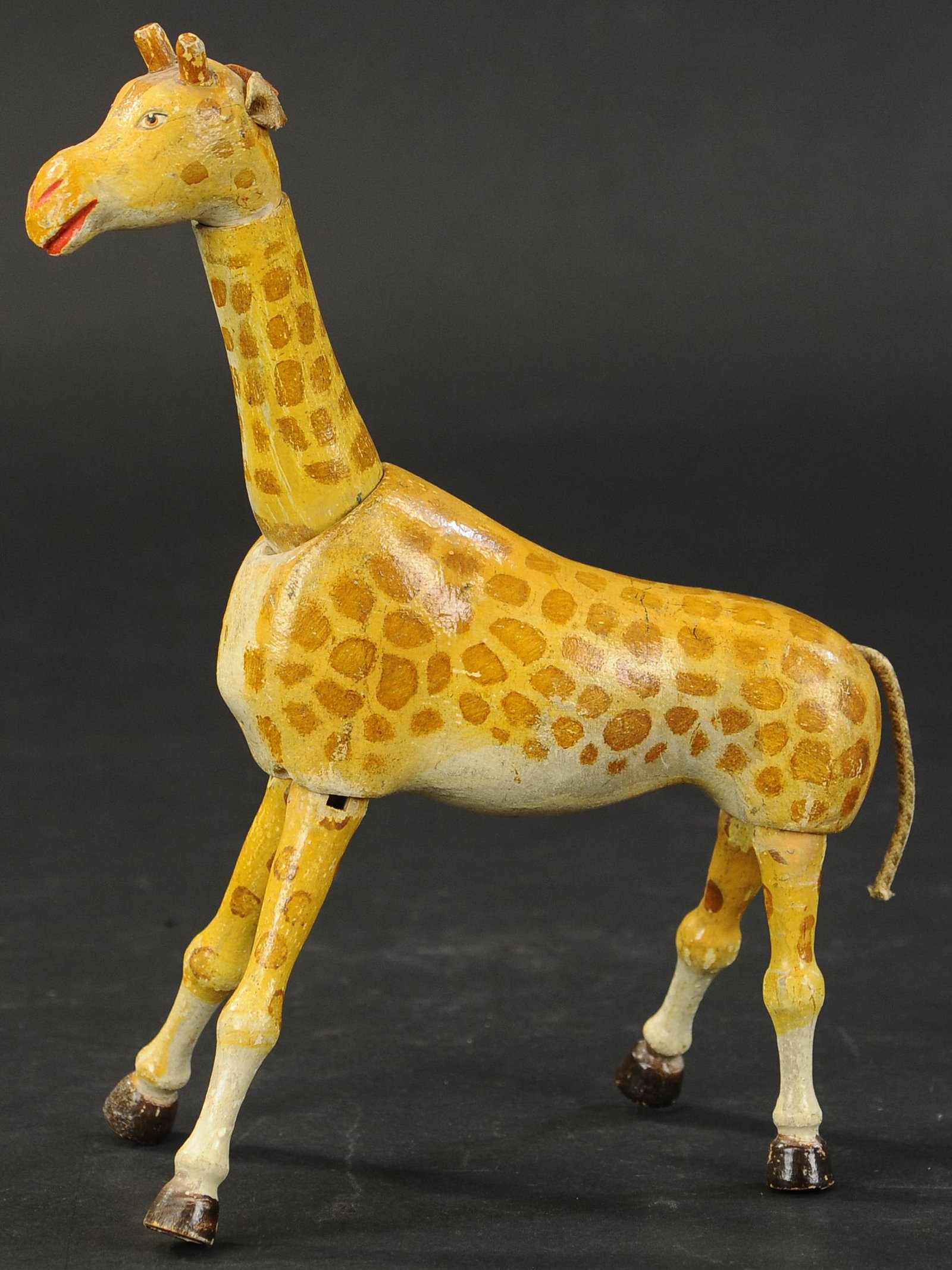 SCHOENHUT GIRAFFE: 517. SCHOENHUT GIRAFFE | Jointed figure, depiction of giraffe in yellow with brown spots, two-part neck and head, painted eyes, wooden antlers, leather ears, and rope tail. 9.5" h. | One replaced ear,