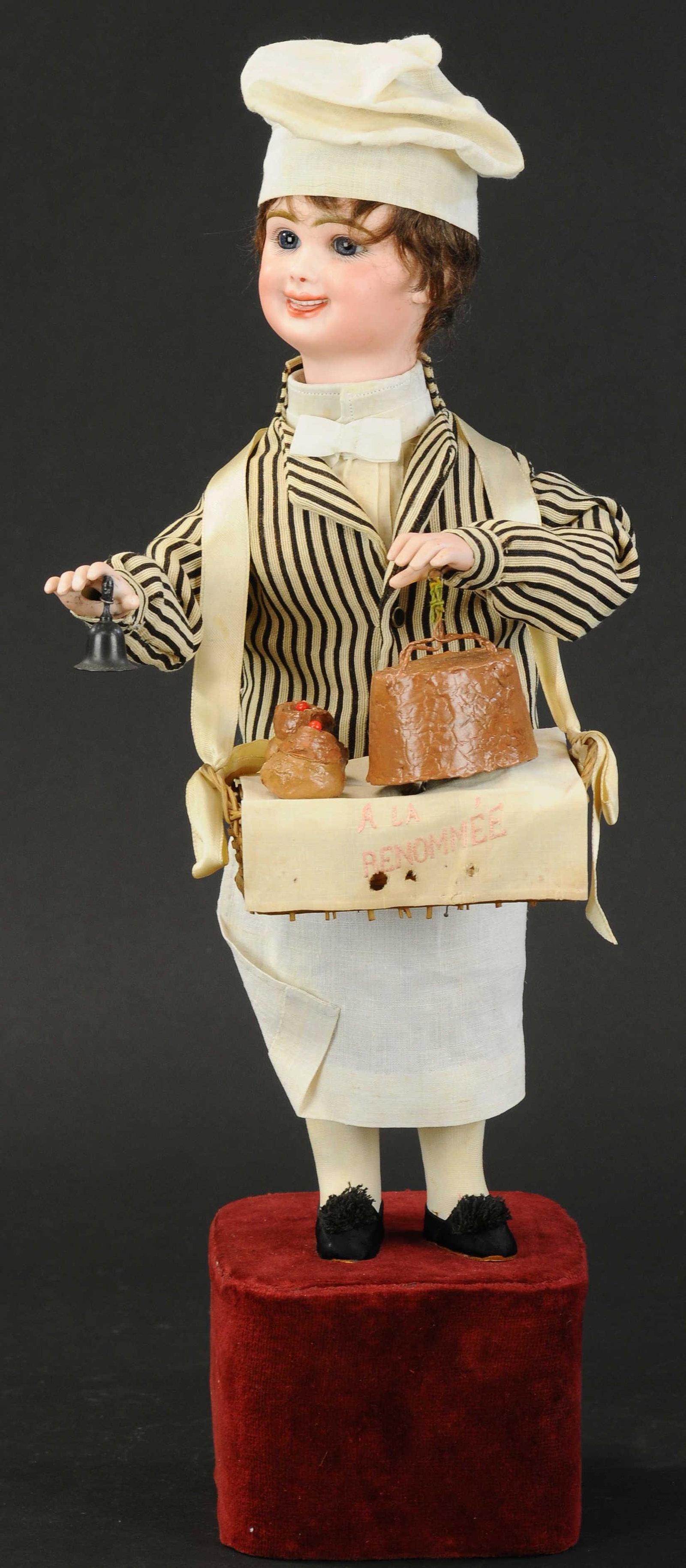 PASTRY CHEF WITH SURPRISE BY LEOPOLD LAMBERT: 1392. PASTRY CHEF WITH SURPRISE BY LEOPOLD LAMBERT | Musical automaton on a velvet covered base of bisque head boy with laughing expression, blue glass paperweight eyes, wide beaming smile, modeled te