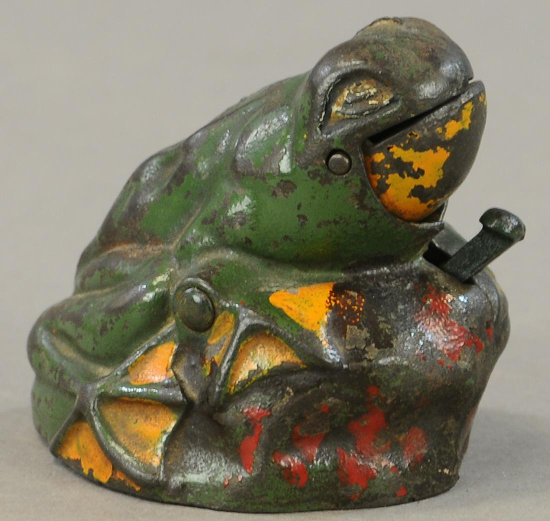 KILGORE FROG ON ROCK MECHANICAL BANK: 197. KILGORE FROG ON ROCK MECHANICAL BANK | 3" l. | Red at front repainted, crack at one side of jaw, lever and trap are replaced. | $150 - $300
