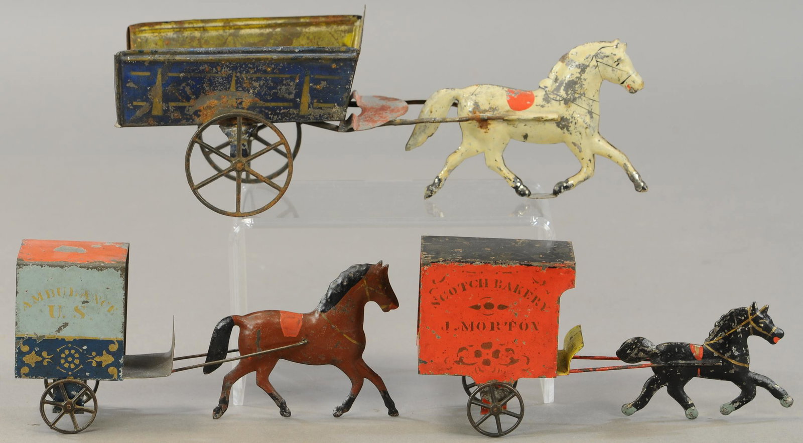 THREE AMERICAN TIN HORSE CARTS: 270. THREE AMERICAN TIN HORSE CARTS | 9" - 12" l. | Bakery wagon is Restored, Ambulance has restoration to sides of cart, some resoldering. | $300 - $600