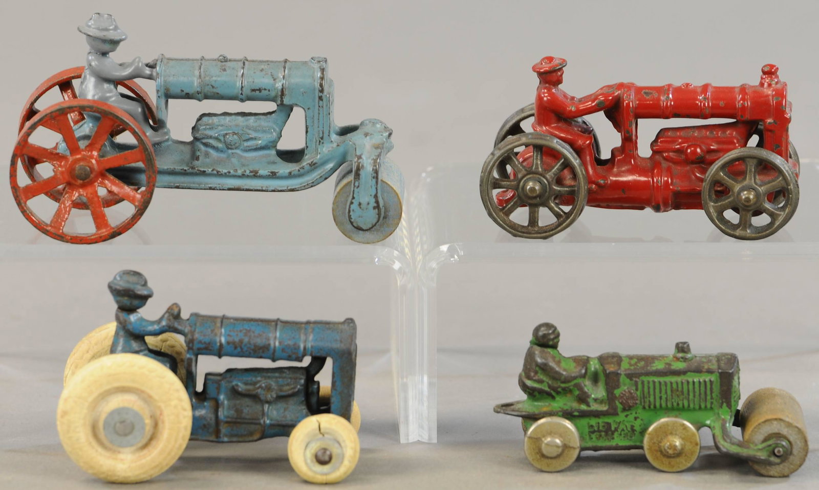 FOUR ARCADE TRACTOR VARIANTS: 331. FOUR ARCADE TRACTOR VARIANTS | 4" - 5" l. | Small red tractor is repainted, small blue tractor has one replaced wheel, large blue driver repainted and has arm reattached, green roller in All Orig