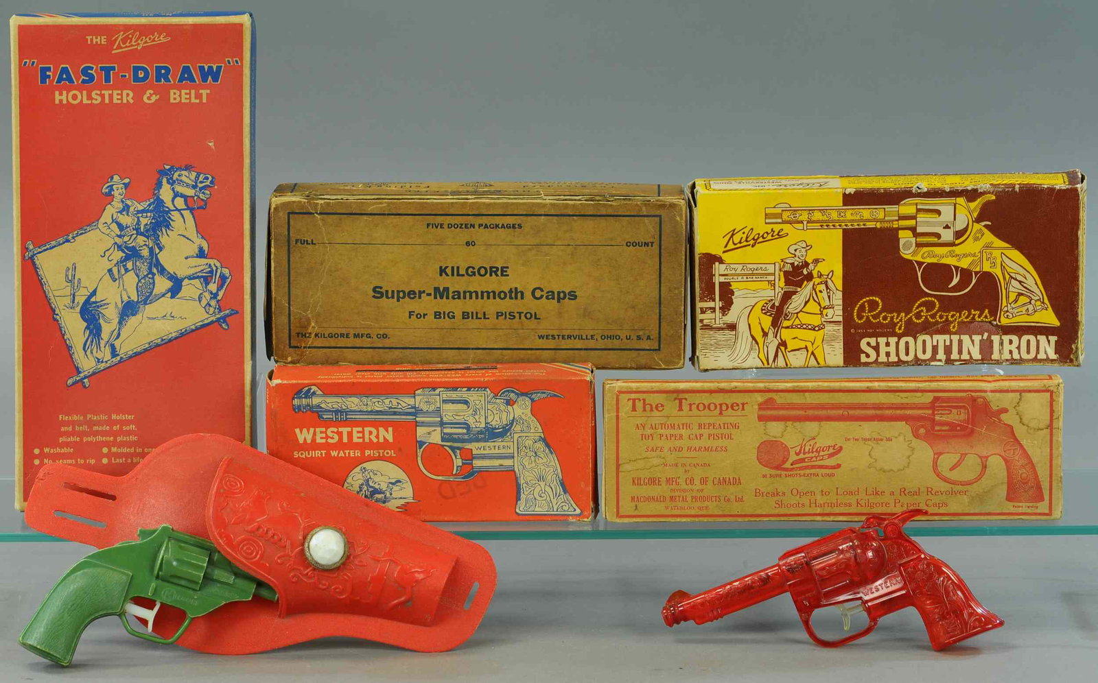 LARGE KILGORE CAP PISTOL GROUPING: 339. LARGE KILGORE CAP PISTOL GROUPING | Lot includes: Boxed 6 shooter, Fast Draw & 3 empty boxes. | 8" - 12" l. | Fast Draw holster set missing belt, boxes are distressed. | $150 - $300