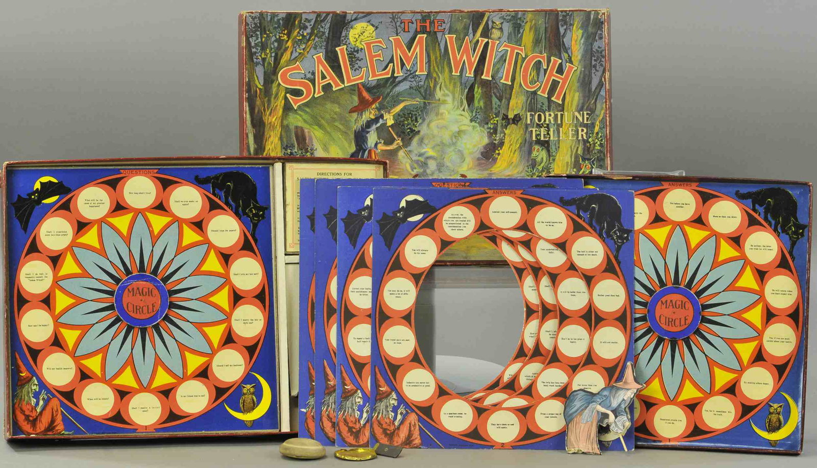 SALEM WITCH FORTUNE TELLER GAME: 431. SALEM WITCH FORTUNE TELLER GAME | Appears to be complete, base of witch is frayed, one hand is missing, top flange of lid is missing. | 14.5" w. | (VG Cond.) | $150 - $300