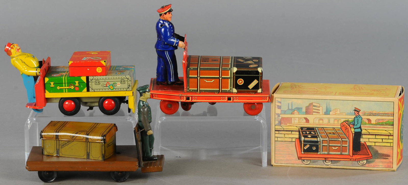THREE WIND-UP LUGGAGE PORTER TOYS: 26. THREE WIND-UP LUGGAGE PORTER TOYS | 6" l. | Box has some torn flaps which are present, toys all working in All Original Condition. | $200 - $400