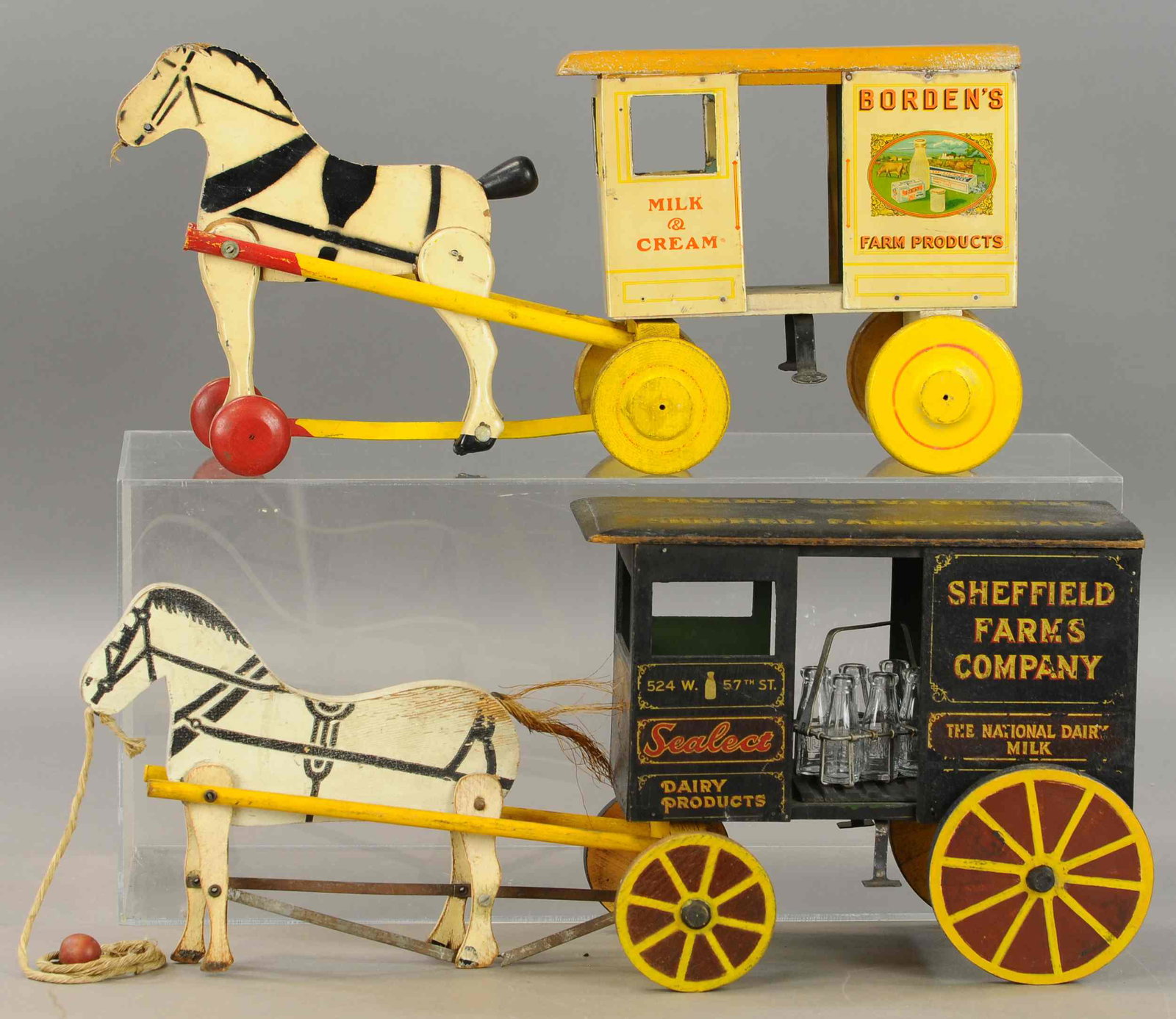 TWO WOOD HORSE DRAWN DELIVERY TRUCKS: 218. TWO WOOD HORSE DRAWN DELIVERY TRUCKS | 20" - 21" l. | Sheffield wagon has metal strap at horses legs split and detached, otherwise both in All Original Condition. | $200 - $400