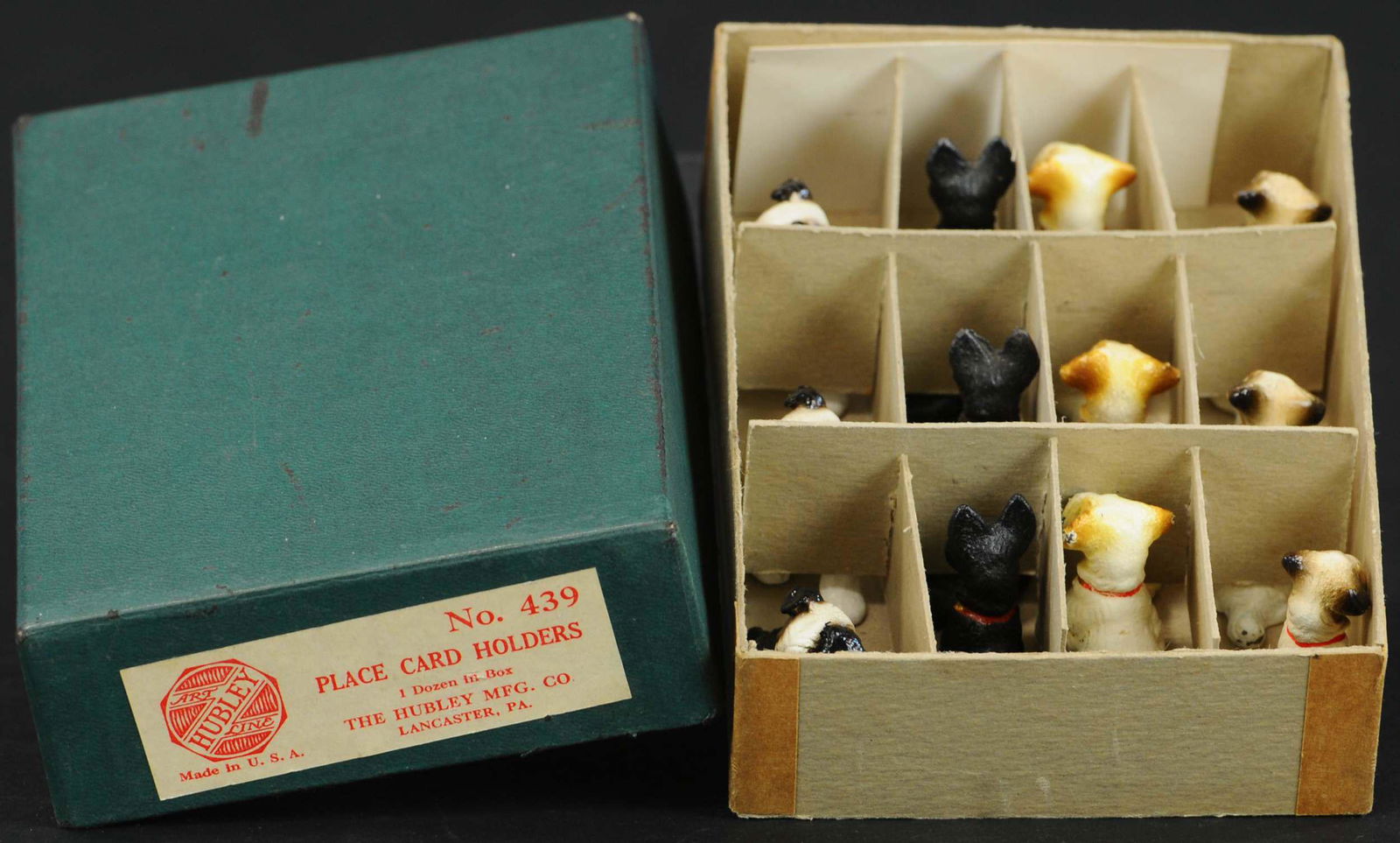 BOXED HUBLEY DOG PLACE CARD HOLDERS: 328. BOXED HUBLEY DOG PLACE CARD HOLDERS | Old store stock of a dozen small dogs, mouths have small slits to hold card. | 1.5" l. | (Near Mint Condition) | $300 - $600
