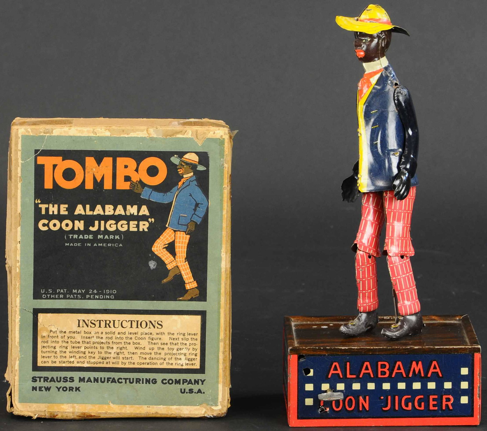 BOXED STRAUSS TOMBO ALABAMA JIGGER TOY: 357. BOXED STRAUSS TOMBO ALABAMA JIGGER TOY | Nice boxed example, Strauss toy is very comparable to the Lehmann example. | 10" h. | Box has tape and glue repairs, toy has one arm reattached at shoulde