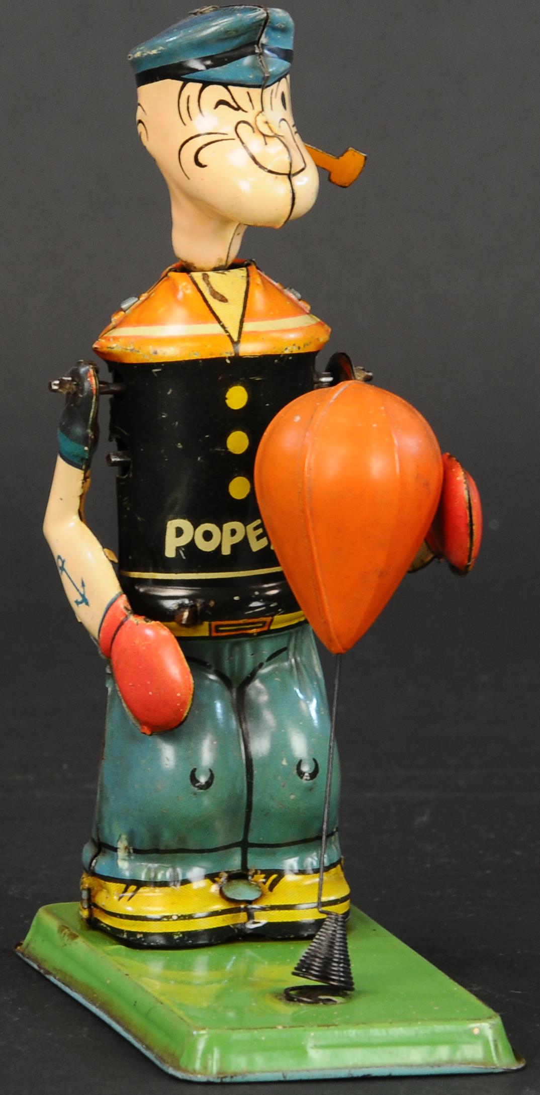 CHEIN POPEYE W/ PUNCHING BAG: 362. CHEIN POPEYE W/ PUNCHING BAG | Desirable example with very fast action. | 7" h. | Dent to celluloid bag, (Excellent Condition) | $700 - $1,000