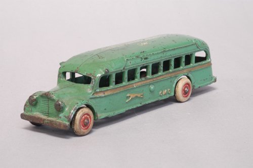 ARCADE GMC GREYHOUND LINES BUS: Circa 1936, cast iron, painted in green body, long gold side stripe, sides embossed with Greyhound logo and letters ''GMC,'' roof stenciled ''Greyhound Lines...GMC,'' rubber tires. 7 3/4'' long.