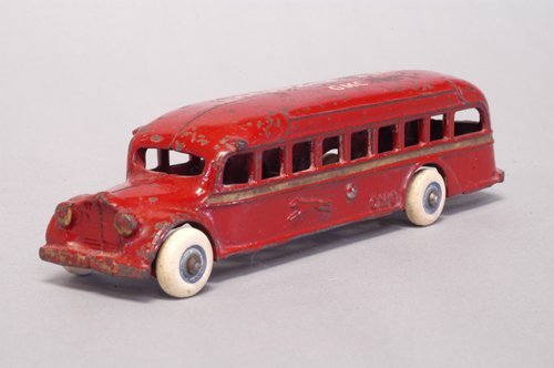 ARCADE GMC GREYHOUND BUS: Circa 1936, cast iron, painted in red overall, gold side stripe, roof reads ''Greyhound Lines...GMC,'' embossed Greyhound on sides, rubber tires. 7 1/2'' long.
