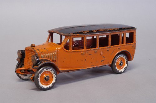 DENT INTERURBAN BUS: Cast iron, painted in orange body with black roof and fenders, cast front headlights, disc wheels are painted white and orange, individual door latches embossed on both sides. 8 1/2'' long.