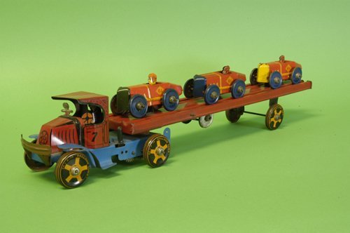 MARX CAR CARRIER: Circa 1930, lithographed tin Mack ''C'' cab done in red, pulls red auto ramp body holding three litho tin racers on ramp supports, windup appears in cab, disc wheels. 22 3/4'' long.