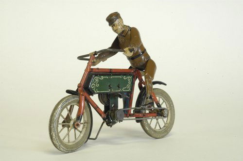HANS EBERL MOTORCYCLE WITH RIDER: Germany, circa 1906, an extremely rare example, handpainted figure depicted on lithographed tin red frame and green tank cycle: the toy has an almost bicycle design with a clockwork mechanism as its m