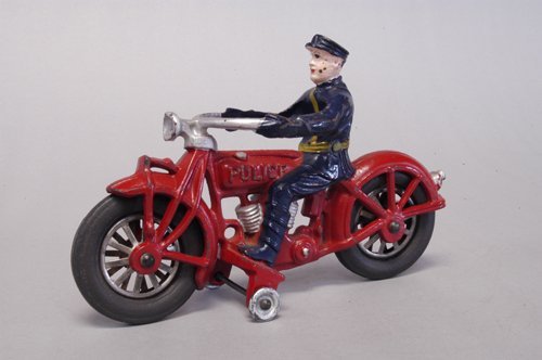 GLOBE MOTORCYCLE WITH POLICE RIDER: C. 1930's, this Philadelphia company had a short tenure in the toy business, cast iron cycle painted in red, blue uniformed driver, rubber tires, any Globe toy is exceedingly rare. 8 1/4'' long.