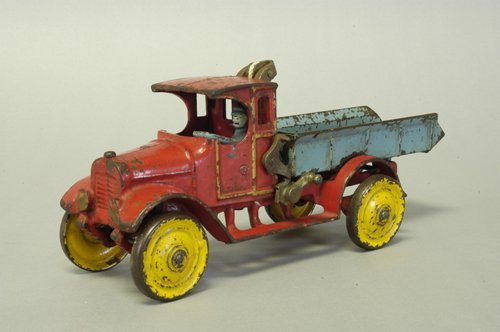 DENT RED AND BLUE BED DUMP TRUCK: Cast iron, a scarce example, done in red cab with blue dump bed and blue driver, disc wheels painted in yellow, features nickel hoist bar on back of cab, dump lever on side. 11'' long.