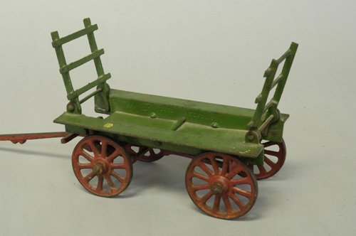 VINDEX HAYLOADER: C. 1928, cast iron, open bed wagon painted in green, features folding stake sides at each end, red hitch and spoke wheels, decal on frame. 8'' long.