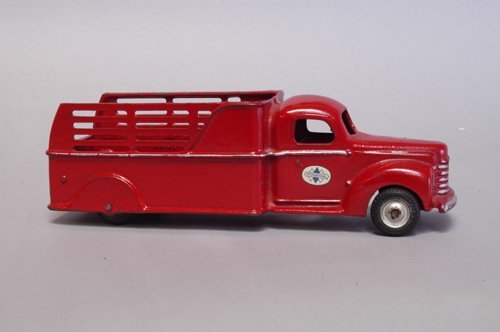 ARCADE BOXED 1941 INTERNATIONAL STAKE TRUCK: Cast iron, painted in fire engine red, silver highlights, enclosed cab, high stake side body, black rubber tires, International decal on doors. 11 1/2'' long.