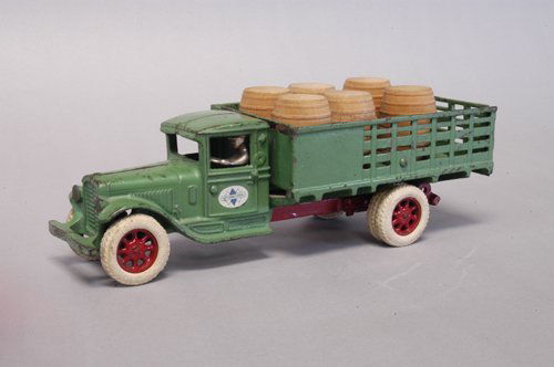 ARCADE INTERNATIONAL STAKE TRUCK: C. 1930's, cast iron, painted in green overall, seated nickel driver, separate opening lift gate, white rubber tires, red spoke wheels, dual rubber on rear, red painted frame under bed. 12'' long.