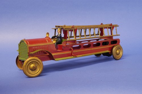 DAYTON FIRE LADDER TRUCK: Pressed steel, done in red with green fenders, gold ladders, seated driver, gold disc wheels, friction powered. 17 1/2'' long.