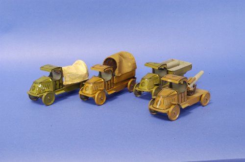 LOT OF FOUR CHEIN MILITARY TRUCKS: Lithographed tin grouping, includes canopy covered transport truck and anti-aircraft truck in brown, together with troop transporter and canopy covered truck in olive green, all depicted as Mack ''C''