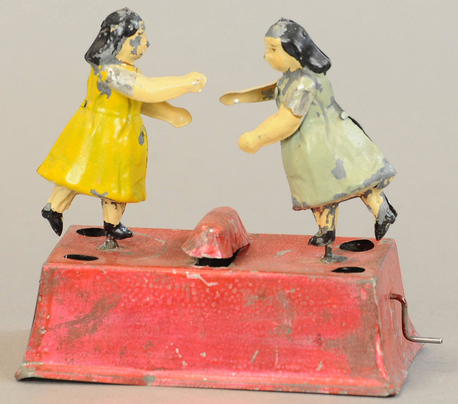 EARLY LITTLE DANCING GIRLS TOY: 42. EARLY LITTLE DANCING GIRLS TOY | Hand paint and spirit painted, hand crank at side to cause both figures to dance. | 5" w. | (Exc. Cond.) | $300 - $600