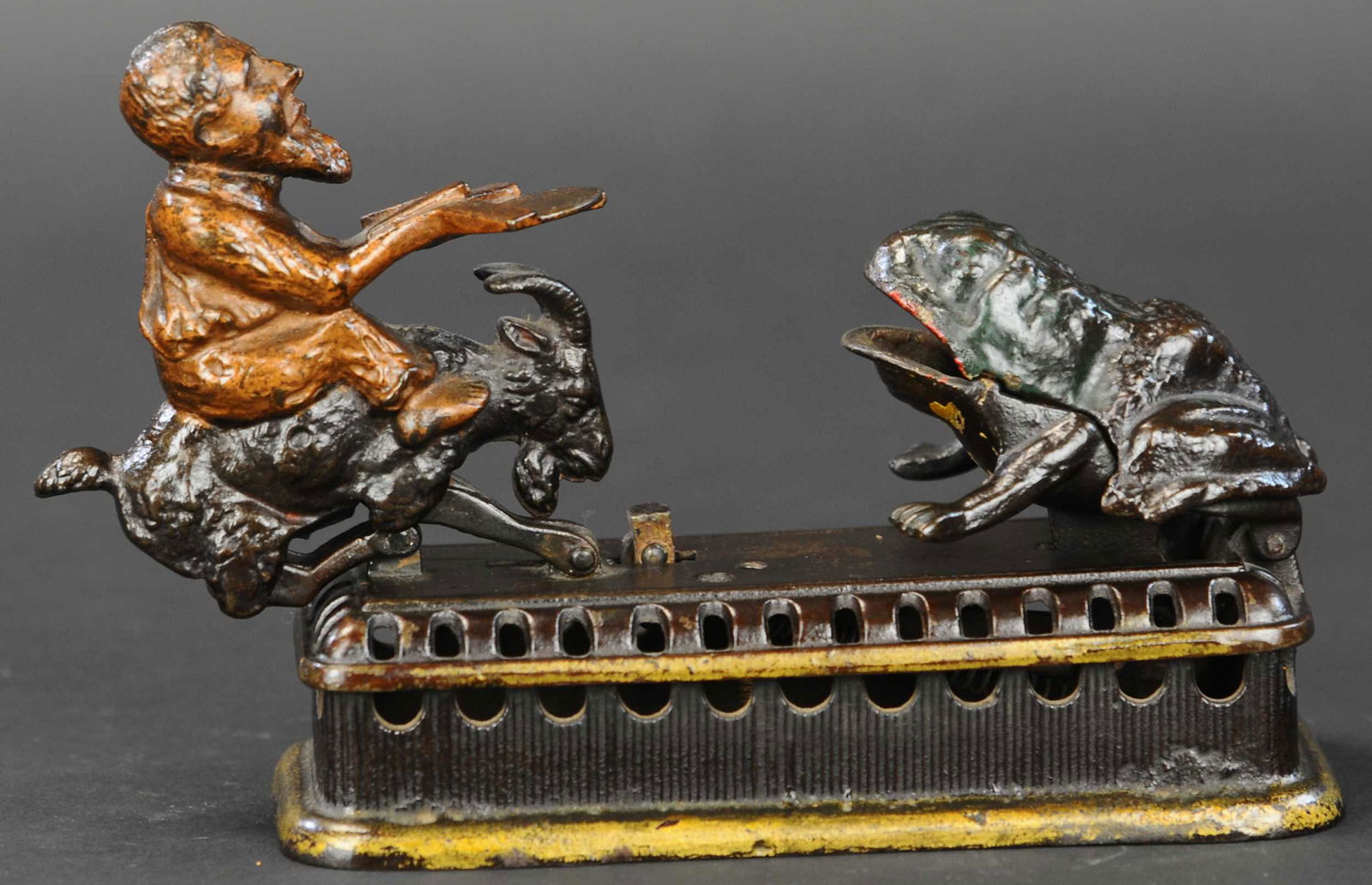 INITIATING SECOND DEGREE MECHANICAL BANK: 155. INITIATING SECOND DEGREE MECHANICAL BANK | Also known as “Goat, Frog and the Old Man,” made by Mechanical Novelty Works of Connecticut, lifting goat’s tail causes spring forward motion and