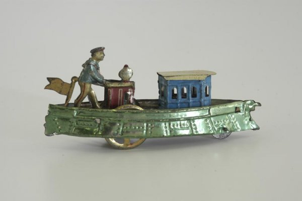 MEIER RIVER BOAT PENNY TOY: Germany, spirit painted in green hull, blue pilot's cabin, white roof, pilot figure stands at helm, flag on stern. 4 5/8" l.