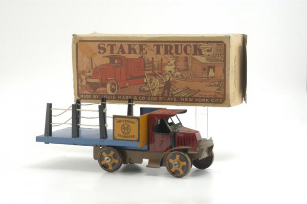 BOXED MARX STAKE TRUCK: Old store stock, lithographed tin, colorful 'C' cab Mack done in red, blue open bed, black removable stakes, brown fenders, seated driver, pull toy. 11 3/4" l.