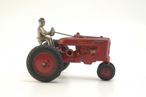 ARCADE FARMALL TRACTOR: c. 1940, cast iron, painted in red overall, decals on hood, seated nickel driver, large black rubber tires with painted centers, gold highlights to engine. 7" l.