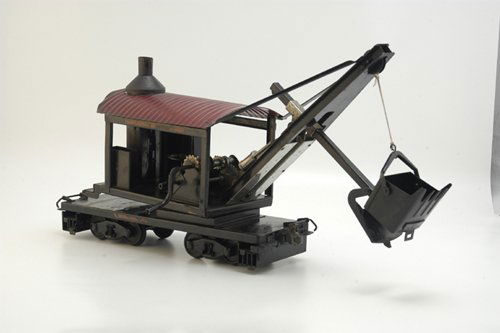 BUDDY 'L' IMPROVED STEAM SHOVEL: 1929, Outdoor Railroad steam shovel model, black housing with red corrugated roof, vertical boiler, nickel plated simulated cylinders, flat car has four wheel trucks, stabilizer extensions at each end