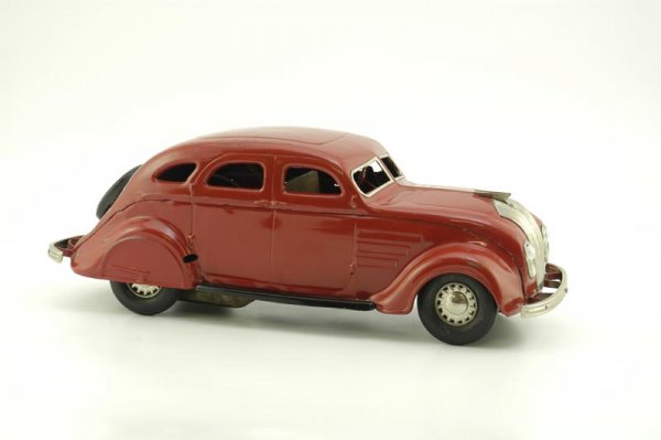 COR-COR CHRYSLER AIRFLOW SEDAN: 1934, pressed steel, painted in red overall, features electric headlights and clockwork mechanism, nickel plated grille, bumpers and hubs, rubber tires, wind-up mechanism, missing key. 16 1/4" l.
