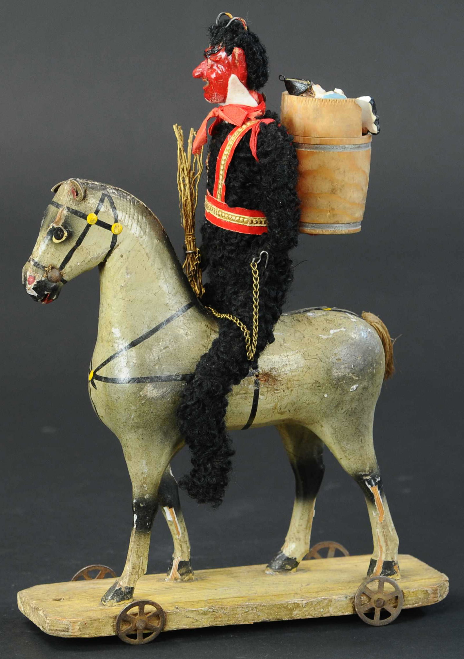 EVIL KRAMPUS ON PONY: 345. EVIL KRAMPUS ON PONY | A wood pony platform toy with a scary looking Krampus, switches and a basket of toys, looking for bad children. | 12" h. | Pony is not original to piece, but is an old one,