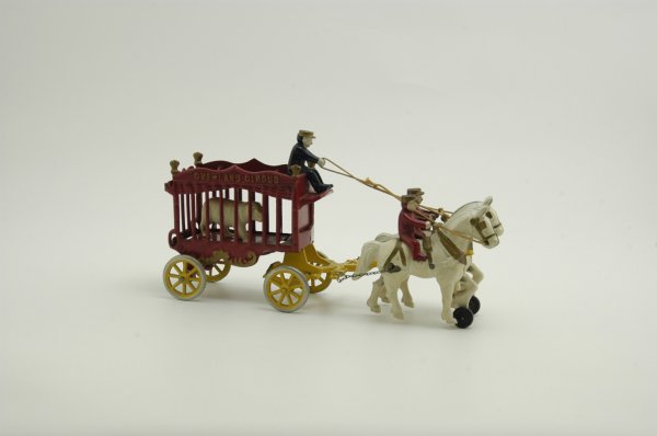 KENTON OVERLAND CIRCUS WAGON: Cast iron, classic animal cage wagon painted in red, team of white horses, two seated riders, roof mounted driver. 14 1/4" l.