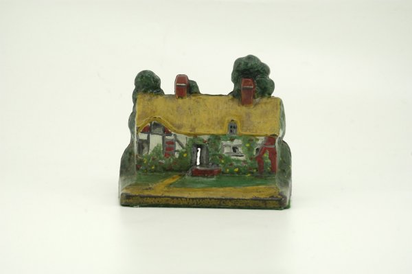 ANN HATHAWAY COTTAGE DOORSTOP: A.M. Greenblatt, #14, depicts colorful cottage with cutout at door entrance, two chimneys and tudor style decor, trees protrude from behind. 7 3/4" w. x 6" h.