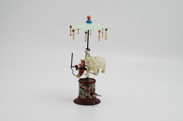 PRE-WAR JAPANESE WHIRLIGIG TOY: Made of celluloid and tin base, clockwork action, allows small clown and elephant to traverse center spiral, canopy top has streamer decor. 12 1/2" h.