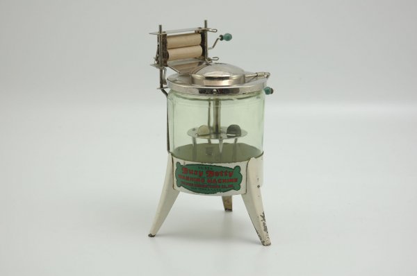HOGE "BUSY BETTY" WASHING MACHINE: Scarce example, white pressed steel frame with light green tinted glass, features a hand crafted wringer and agitator, nickeled lid, decal on front. 10" h.
