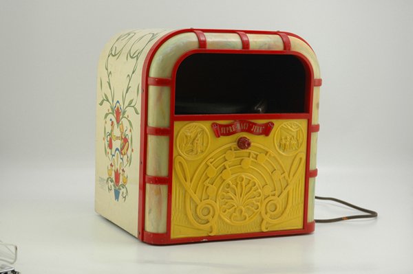 SUPRE-MACY JUKE BOX RECORD PLAYER: Lindstrom, lithographed tin, made to resemble a full scale juke box, this table model record player has colorful yellow and red front, records slide onto turntable from front panel, 115 volts, has not