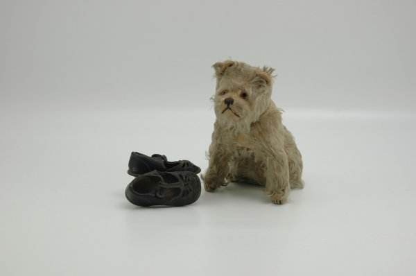 SCHUCO YES-NO TERRIER & DOLL'S SHOES: Unusual glass eyed plush mohair seated dog with stitched nose and paws, when tail is moved, head turns side to side or up and down, together with pair of black leather doll's shoes suitable for a todd