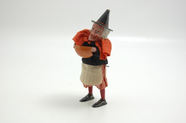 GERMAN MECHANICAL WITCH: Ingenious wind up piece , which when wound, appears to shake up her bowl of witches brew; composition face is rather comical with exaggerated features, she wears a striped linen skirt with felt shirt,