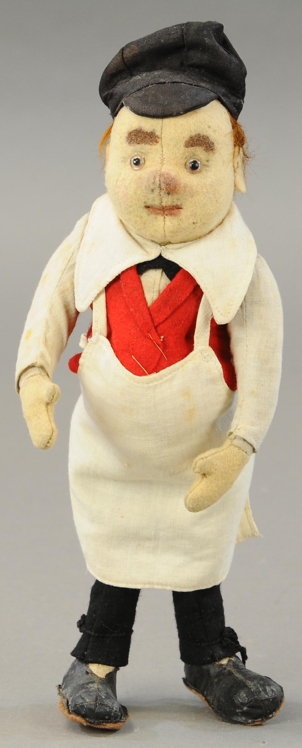 ALL FELT DOLL PORTRAYING A BUTCHER: 1229. ALL FELT DOLL PORTRAYING A BUTCHER | Glass eyes all felt figure, made in a "Steiff-like" manner with horizontal center facial seam, yet lacking the superb quality of Steiff, so conceivably Bing,