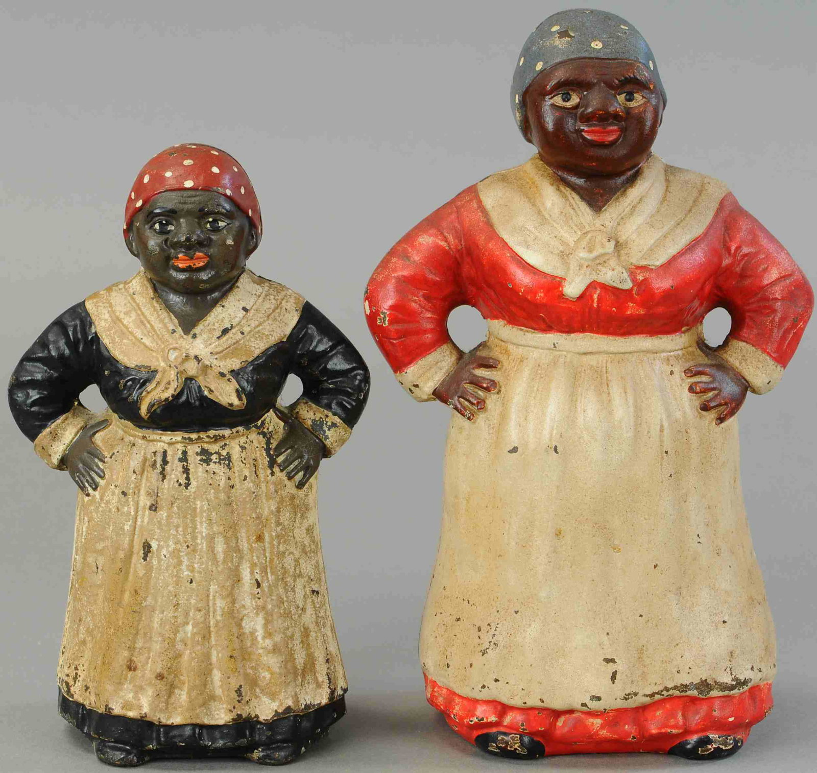 TWO MAMMY VARIATION DOORSTOPS: 1327. TWO MAMMY VARIATION DOORSTOPS | Full figured, larger size w/ red dress is Hubley, detailed casting on other. | 10" h. | (Excellent Condition) | $200 - $400