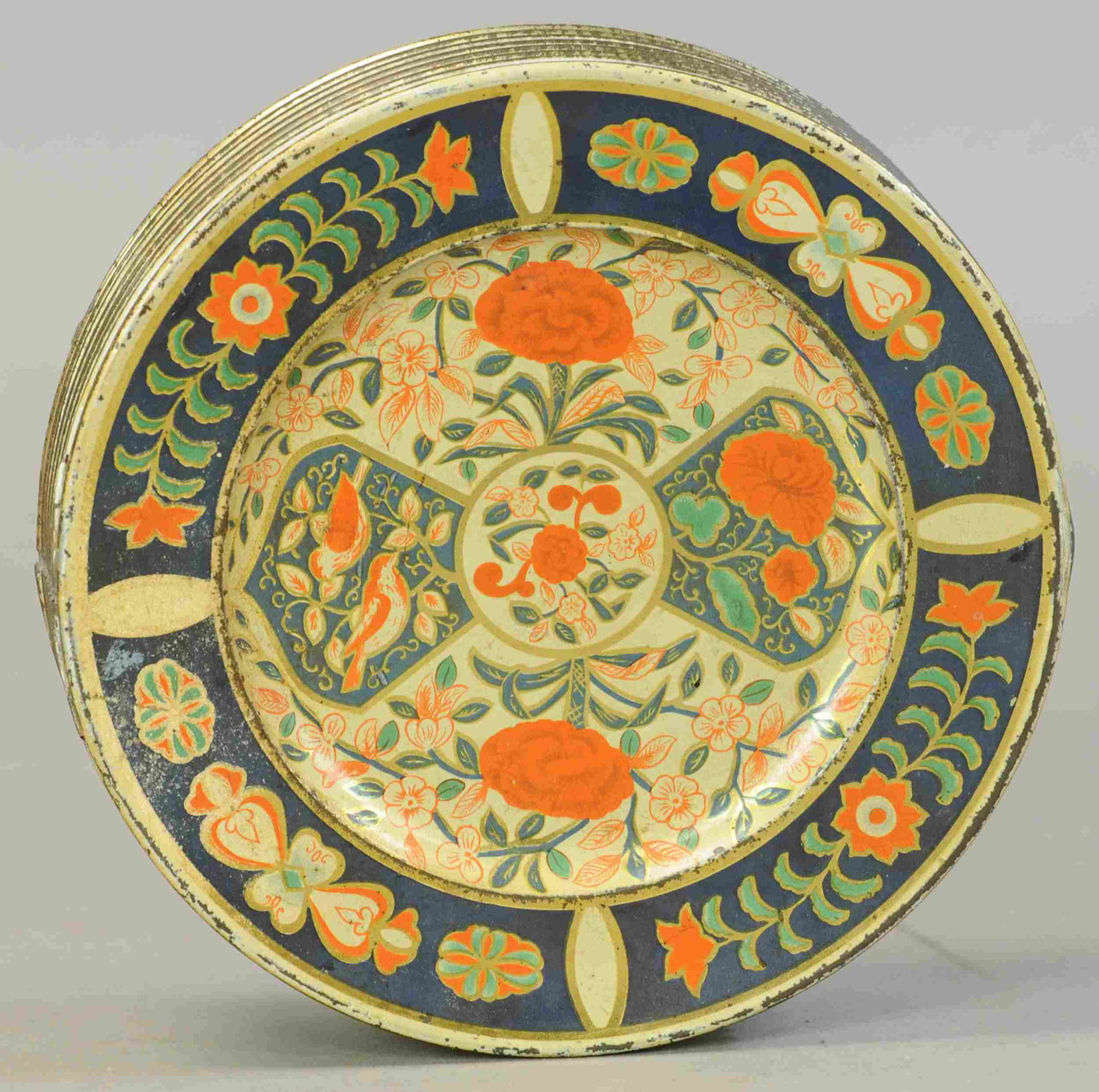 STACK OF PLATES BISCUIT TIN: 275. STACK OF PLATES BISCUIT TIN | Huntley and Palmer, first produced in 1906, detailed lithography of floral and vine pattern in blue and red, emulating a stack of Derby plates, with hinged top. | 8.