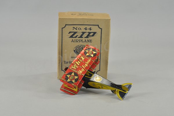GIRARD "ZIP WHIZ" AIRPLANE WITH ORIGINAL BOX: Lithographed, very colorful bi-wing, single propeller example, key wind operates prop, well detailed graphics, billed as the "Sky Fighter," scarce example. 9" l.