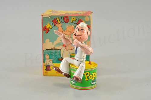 LINEMAR SMOKING POPEYE IN ORIGINAL BOX: Litho tin battery operated toy, wokring. King Features copyright. Made in Japan c. 1958. Popeye sits on over-sized spinach can, smokes pipe and waves. 9 1/2" h.